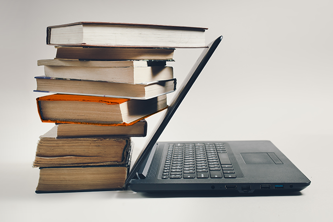 Stack of books next to a laptop